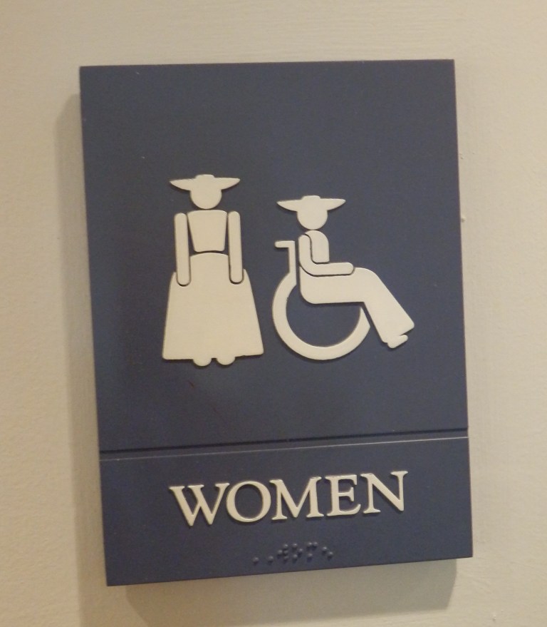 Colonial Williamsburg ladies room sign with figures wearing in colonial dresses